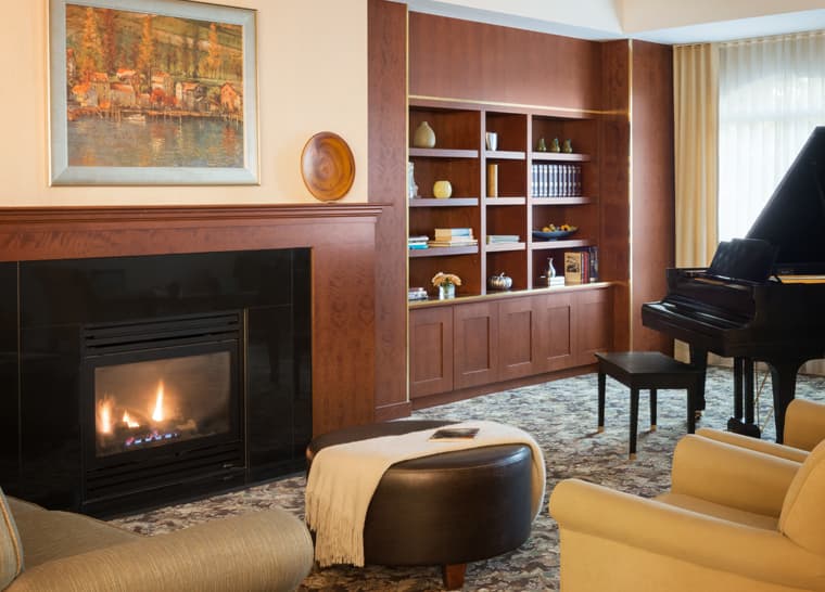Fireside lounge with grand piano at Amica Newmarket senior living residence.