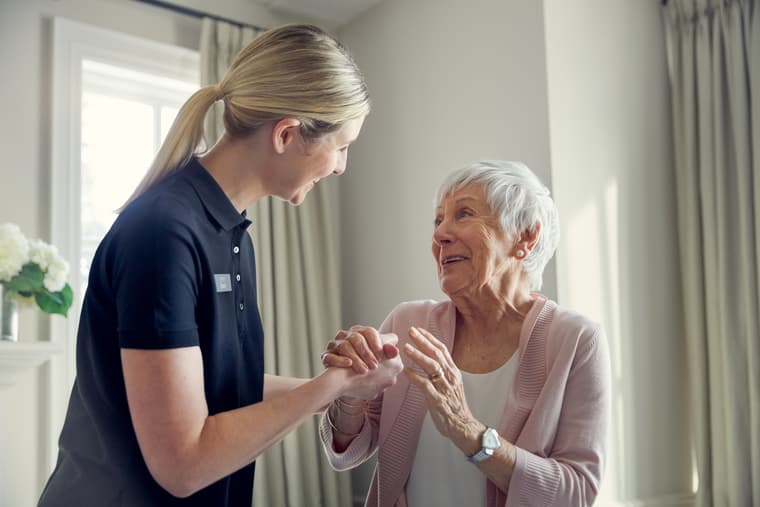 Lifestyle Shoot - Caregiver Supporting Female Resident Female caregiver supporting and smiling with female resident